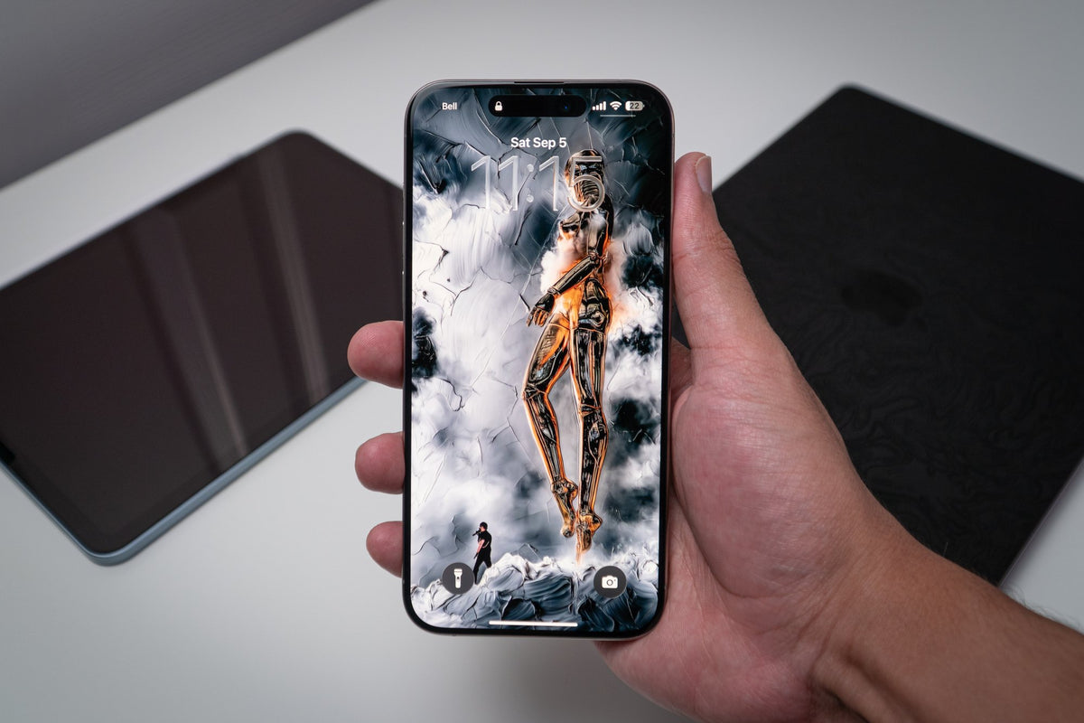 Gold robotic figure in smoke, wallpaper on an iPhone lock screen, held in hand