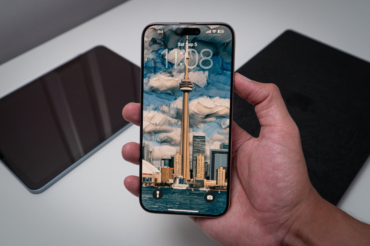 CN Tower daytime skyline wallpaper on an iPhone lock screen, held in hand